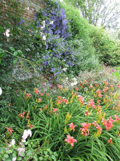 A herbaceous border at Sissinghurst with a 16C brick wall behind.